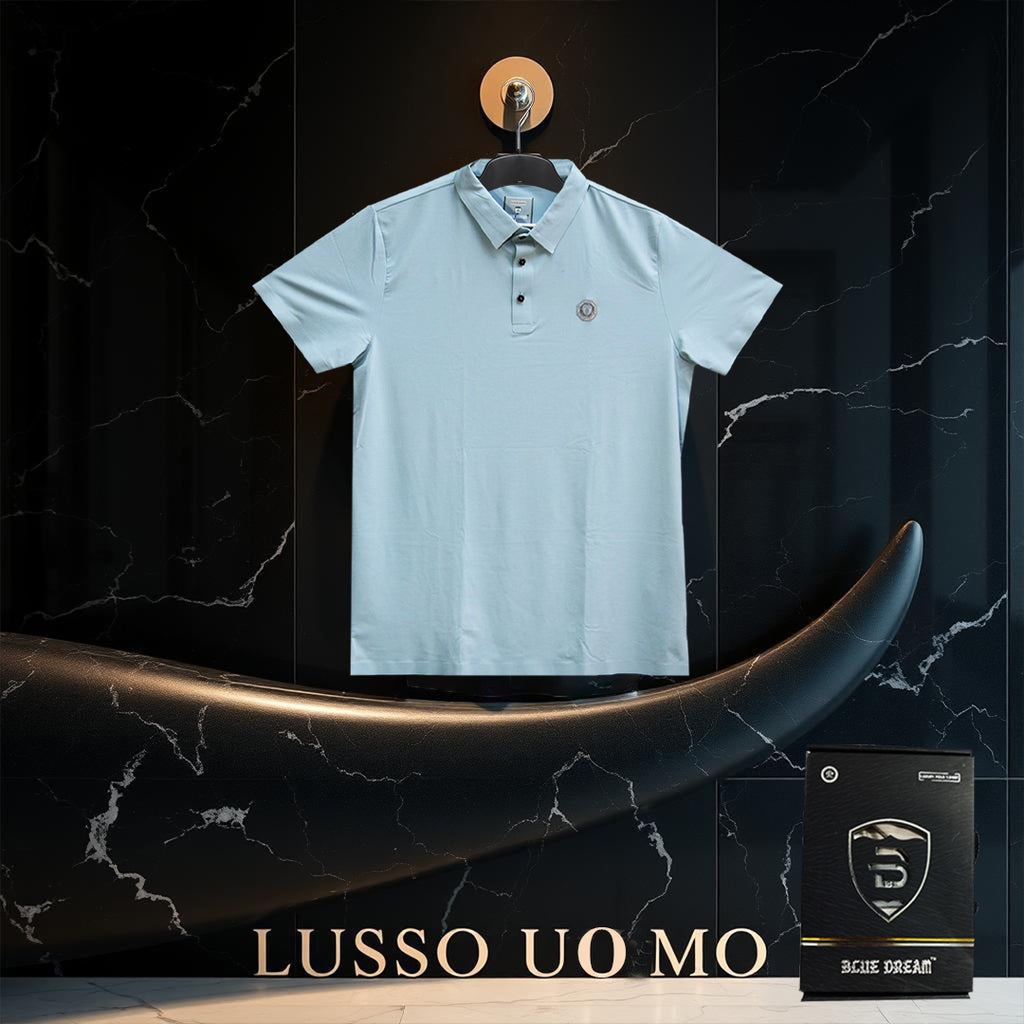 Light blue polo shirt on a hanger with 'Lusso Uomo' branding and a black box labeled 'Blue Dream' on a dark marble background.